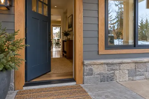 Exterior entry showing a fitted door, threshold, window and surrounding cladding